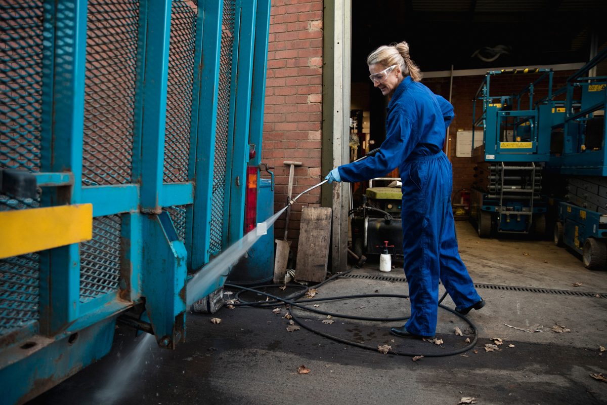 Technician cleaning plant equipment with a Kärcher high-pressure washer